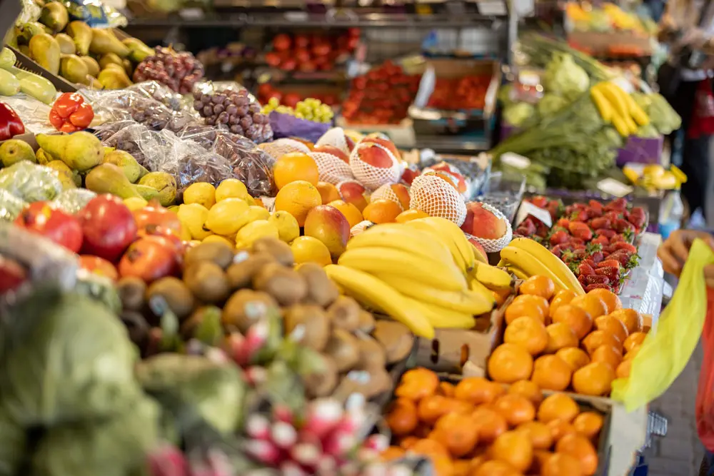 Display of fresh vibrant fruits including bananas, oranges, pears, and strawberries arranged at a local market stall.
